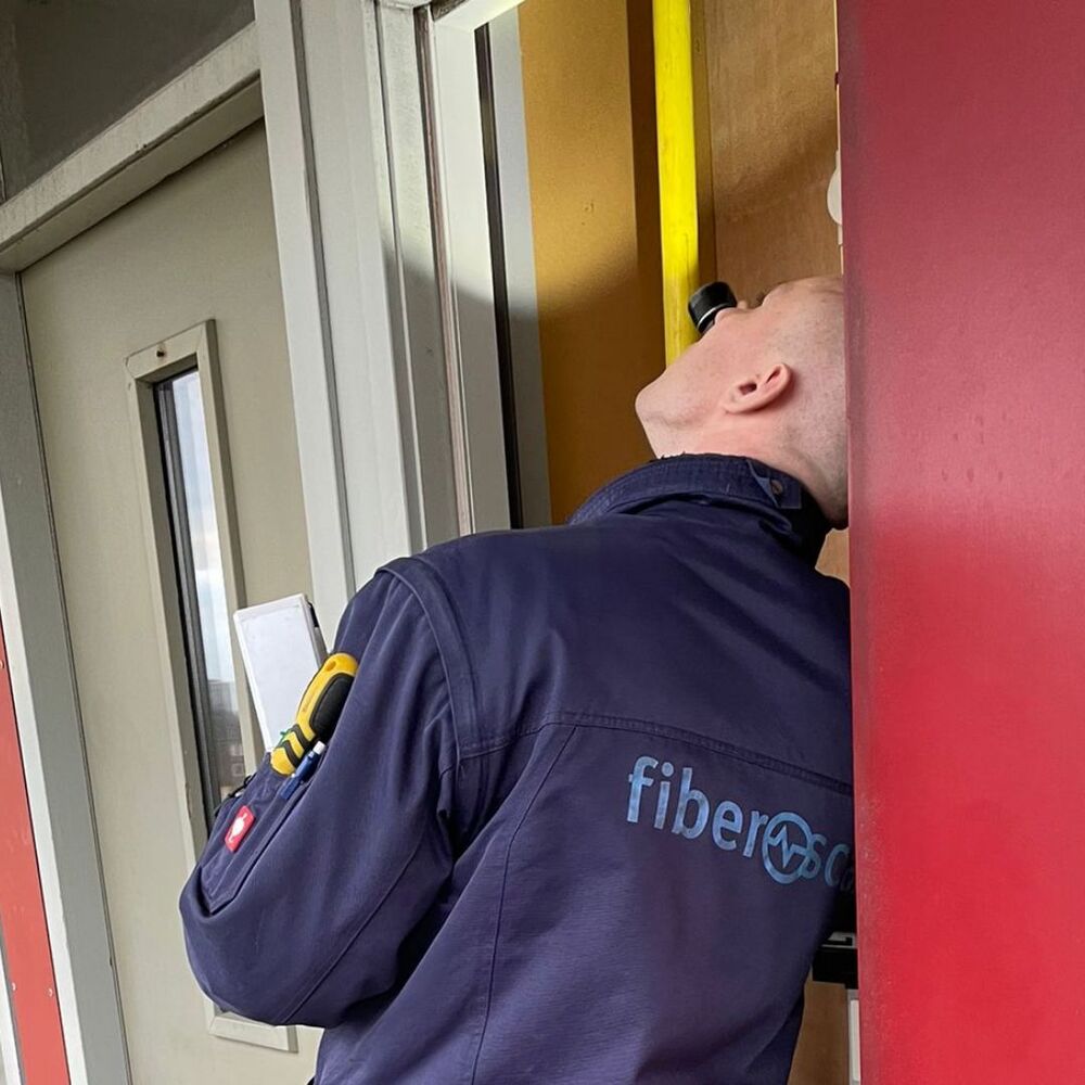 Deskundig inventariseerder asbest die een zaklamp schijnt in een deuropening.